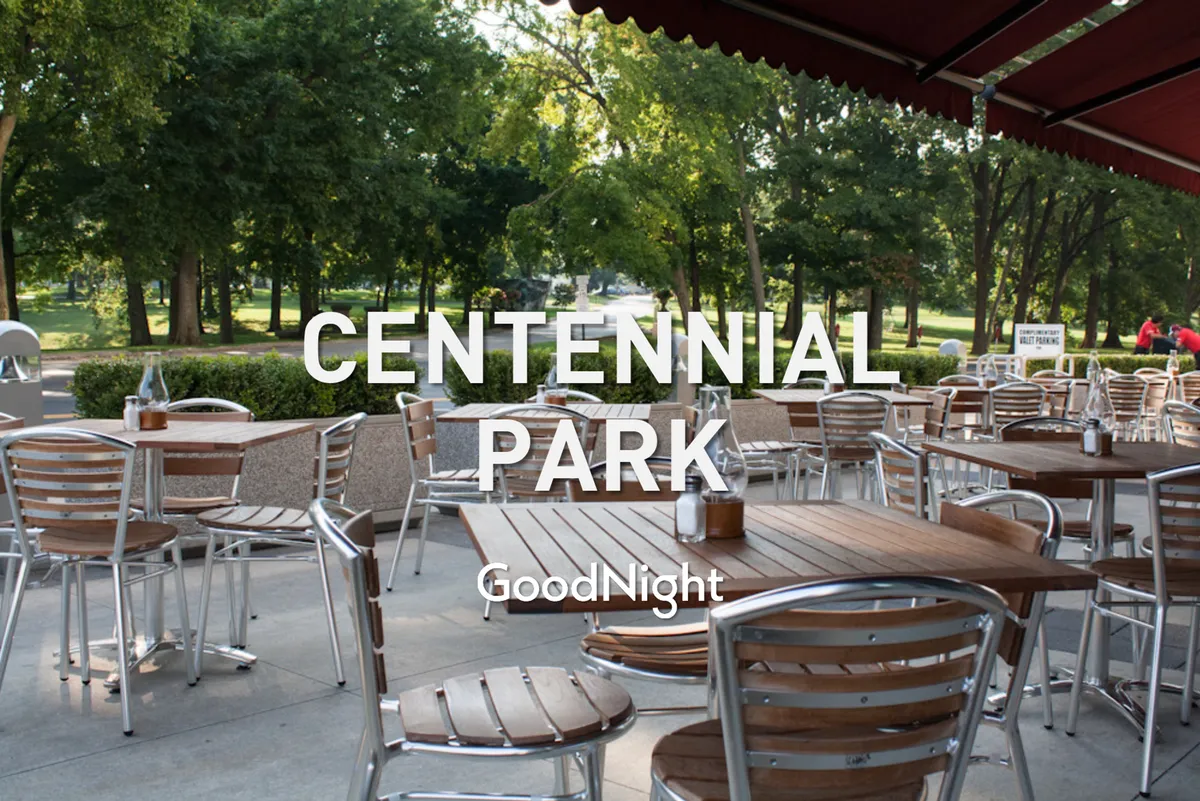 An inviting outdoor seating area set amidst lush greenery, featuring wooden tables and comfortable chairs. The relaxed setting is ideal for morning coffee, casual work sessions, or unwinding after a productive day.